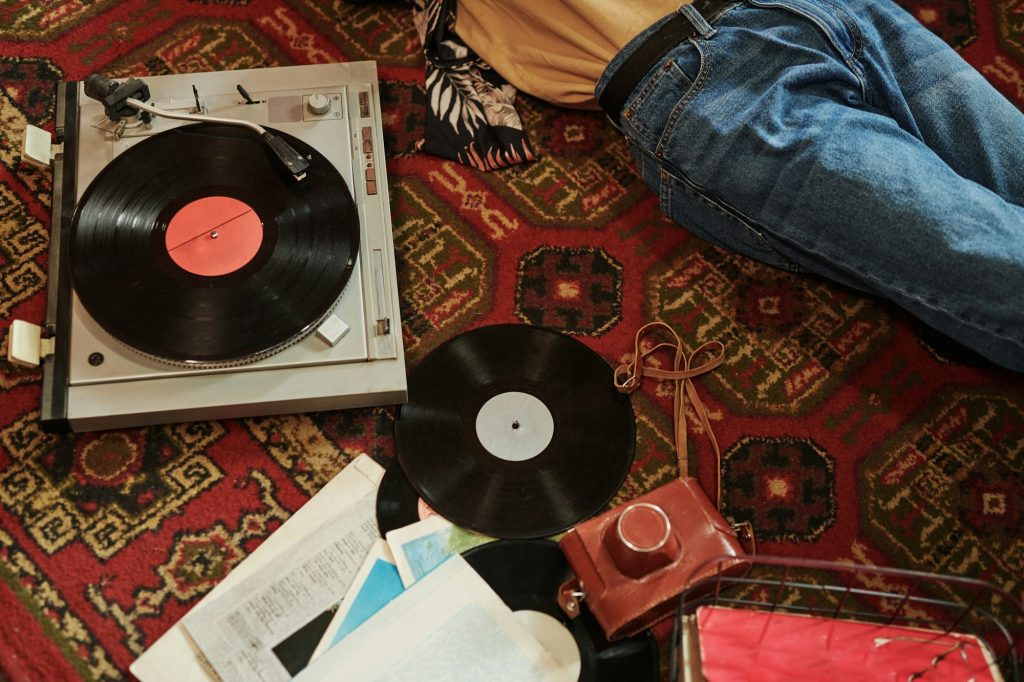 Part of young man in blue jeans relaxing on red carpet in living room